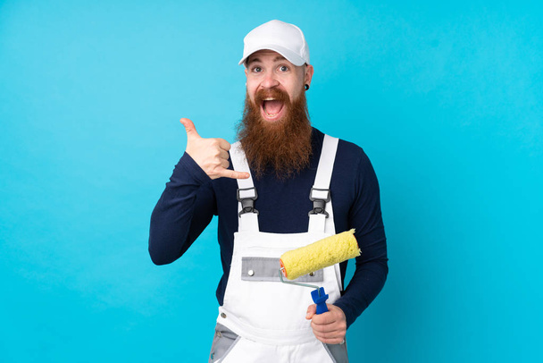 Художник с длинной бородой на изолированном синем фоне делает телефонный жест
 - Фото, изображение