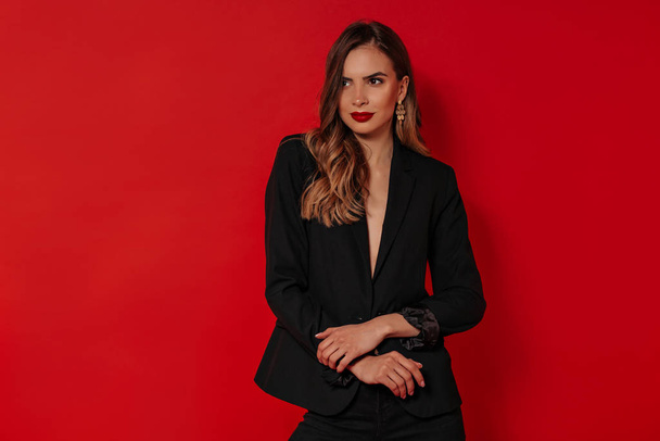Beautiful woman with evening make up wearing black jacket posing over isolated red background. Birthday, Valentines day, holiday - Photo, Image