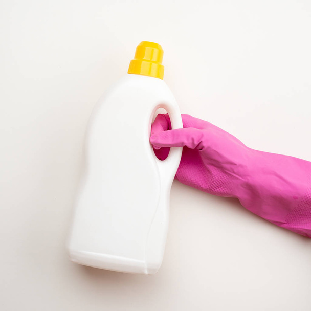 Fechar a mão vestindo em luva de látex segurando uma garrafa de detergente w
 - Foto, Imagem