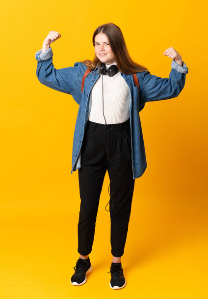 Student ukrainian teenager girl over isolated yellow background celebrating a victory - Foto, Imagen