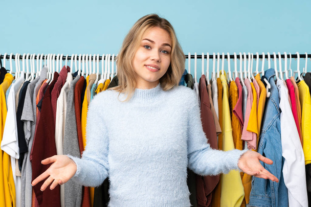 Teenager Russian girl buying some clothes isolated on blue background smiling - Photo, Image