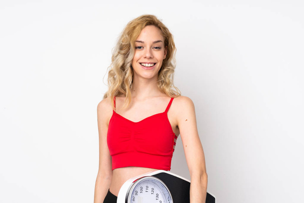 Young blonde woman isolated on white background with weighing machine - Photo, Image