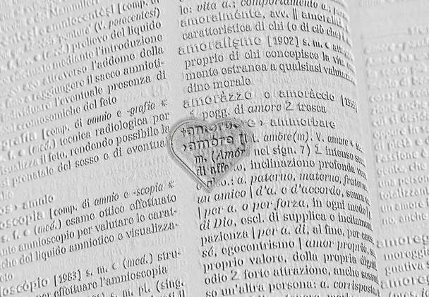 The word love, amore, engraved with letters in a heart-shaped frame on a gray engraved words background - Photo, Image