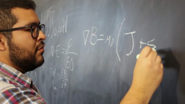 Fortgeschrittener Physikstudent skizziert Gleichungen auf Tafel - Filmmaterial, Video