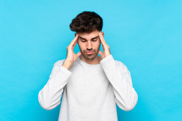 Young man over isolated blue background with headache - 写真・画像