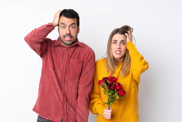 Paar am Valentinstag hält Blumen über isoliertem Hintergrund nimmt Hände auf den Kopf, weil Migräne hat - Foto, Bild