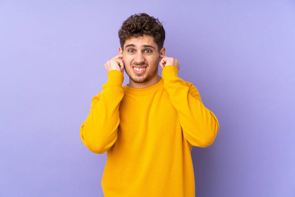 Caucasian man isolated on purple background frustrated and covering ears - Photo, Image