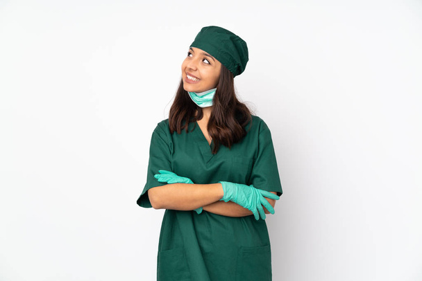 Chirurgo donna in uniforme verde isolato su sfondo bianco guardando verso l'alto sorridendo
 - Foto, immagini