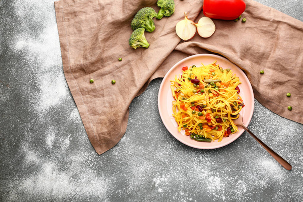 Plaat met lekkere pasta en groenten op grijze ondergrond - Foto, afbeelding
