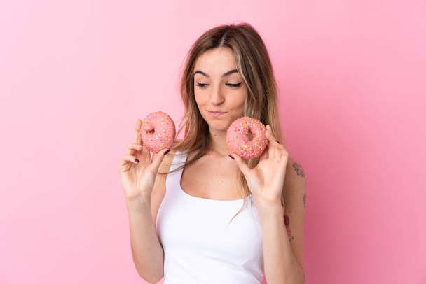 Jovem mulher sobre isolado fundo rosa segurando donuts - Foto, Imagem