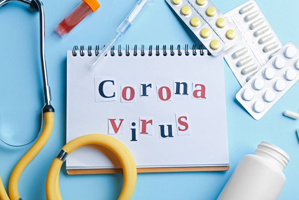 Flat lay composition of medications and notebook with words CORONA VIRUS on light blue background - Foto, afbeelding