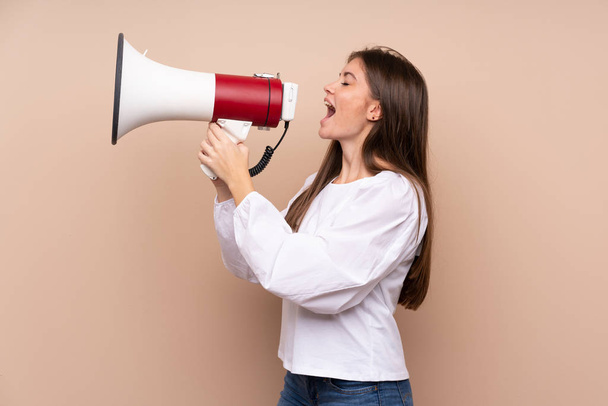 Young girl over isolated background shouting through a megaphone - Foto, imagen