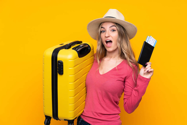 若いです女性以上隔離された黄色の背景で休暇でスーツケースとパスポート - 写真・画像