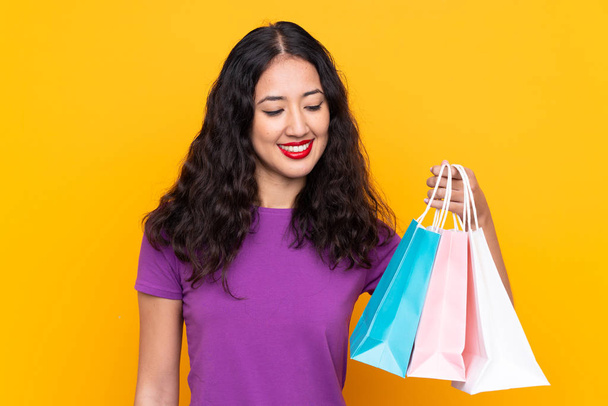 Mulher chinesa espanhola com saco de compras sobre fundo isolado com expressão feliz
 - Foto, Imagem