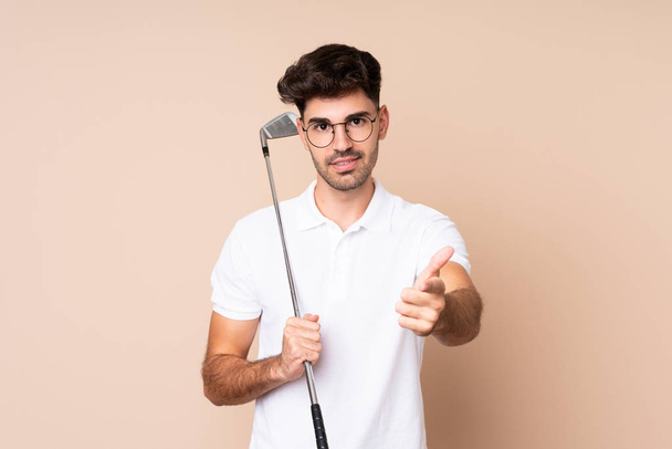 Young man over isolated background playing golf and pointing to the front - Foto, imagen