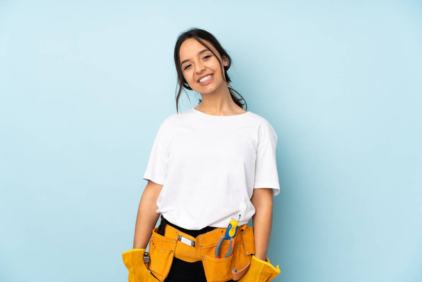 Young electrician woman isolated on blue background laughing - Photo, image