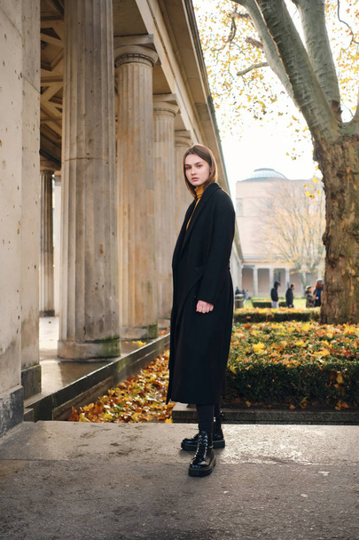 Beautiful casual girl in black coat thoughtfully walking around  - Фото, зображення
