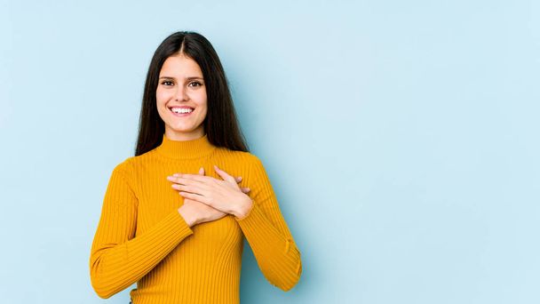 Young caucasian woman isolated on blue background laughing keeping hands on heart, concept of happiness. - Photo, image
