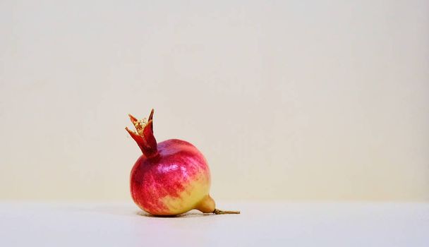 Red and yellow dwarf pomegranate fruit on a beige background - Foto, Imagem