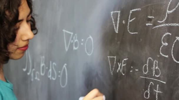 Slimme jonge Latijnse vrouw die Maxwell 's vergelijkingen op schoolbord schrijft - Video