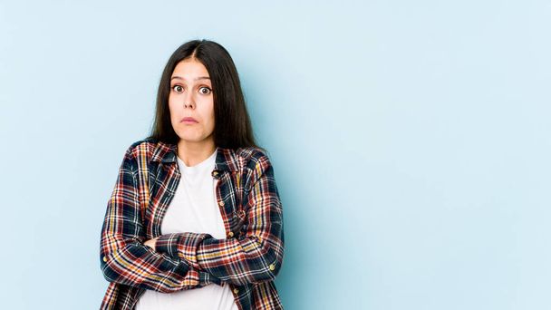 Young caucasian woman isolated on blue background shrugs shoulders and open eyes confused. - Photo, image