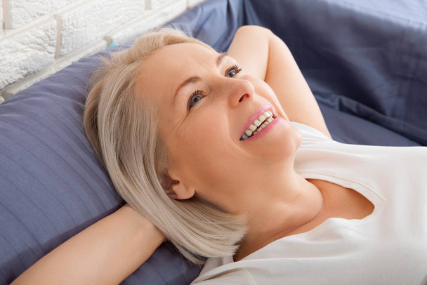 Beautiful middle woman sleep close her eyes smile sleep and sweet dream on bed in bedroom in the morning feeling so relax and comfortable. Healthcare and sleep concept - Valokuva, kuva