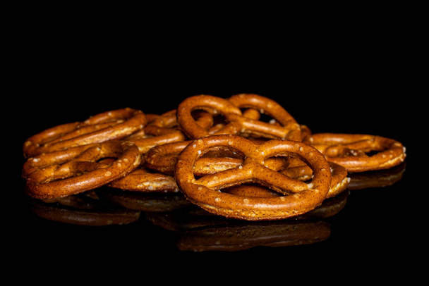 Salty brown pretzel isolated on black glass - Fotoğraf, Görsel