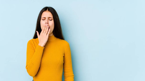 Young caucasian woman isolated on blue background yawning showing a tired gesture covering mouth with hand. - Photo, Image
