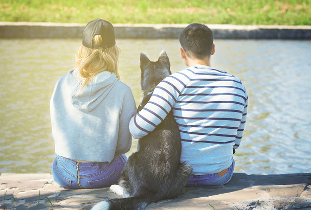 guy, girl and dog are sitting on the riverbank and looking at the water - Photo, image