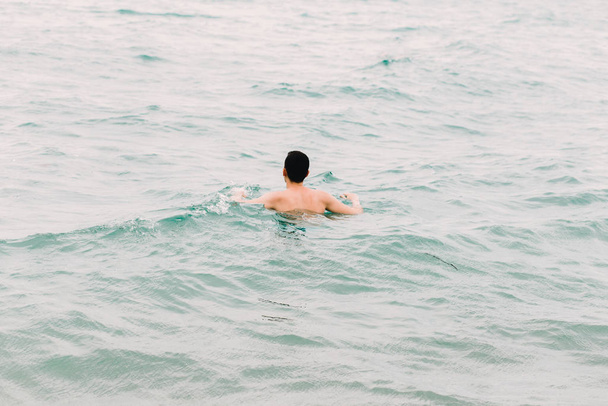 a young guy is swimming in the blue clear water of the ocean - 写真・画像