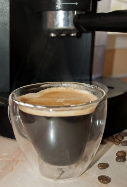 Kahvinkeitin. Läheltä piti. Kahvia kaksiseinäisessä lasimukissa. Kahvi kaadetaan kahvinkeittimestä aamulla
 - Valokuva, kuva