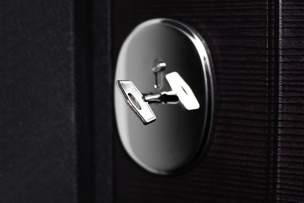 Close-up of steel key in lock of modern apartment house. Black background. - Foto, Imagen