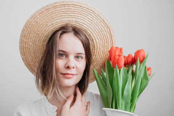 молодая женщина в шляпе с красным букетом тюльпанов
  - Фото, изображение
