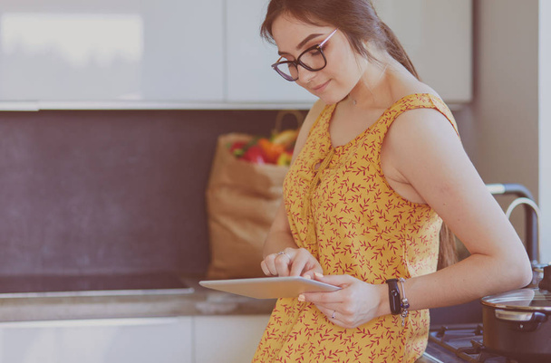 beautiful young woman using a digital tablet in the kitchen - Foto, afbeelding