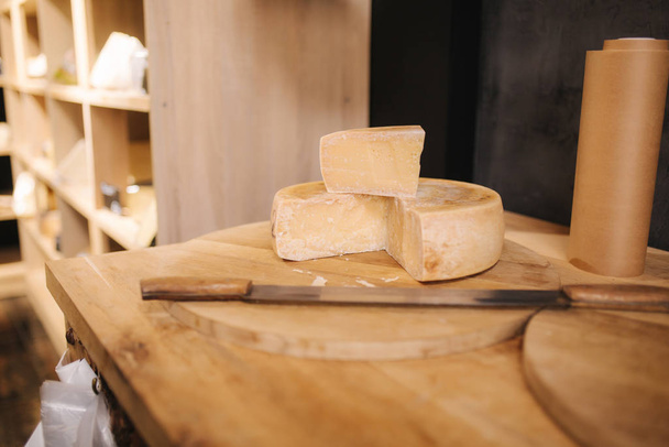 Queso con cuchillo de madera en tienda de quesos
 - Foto, Imagen