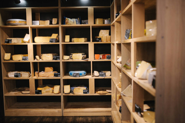 Estante con queso en la tienda de queso. Surtido de diferentes tipos de queso
 - Foto, Imagen