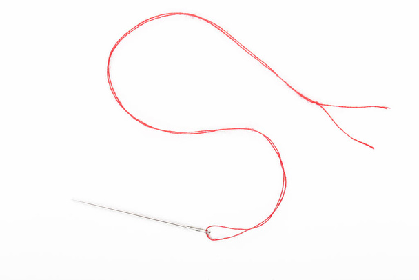 Sewing needle with red thread on the white background - Photo, Image
