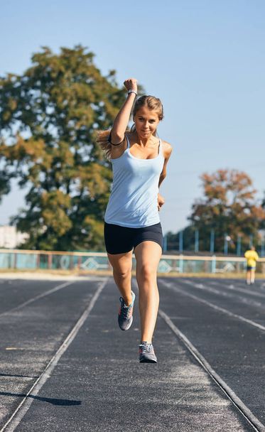 girl is keenly jogging in the stadium - Photo, image