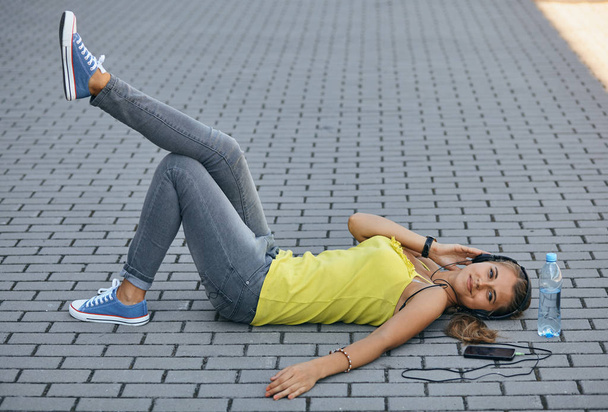 girl lying on the sidewalk in the summer and quietly listening to music - Foto, Imagen