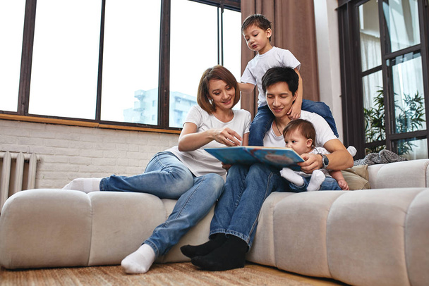Happy international family concept. Dad, mom, son and little daughter posing for a camera at home, are engaged in home parenting. Home holidays, parenting, concept children and parents. - Foto, imagen