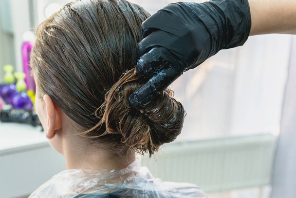 junges Mädchen mit Haarbehandlungsmaske im Schönheitssalon, junges Mädchen während des Pflegeprozesses - Foto, Bild