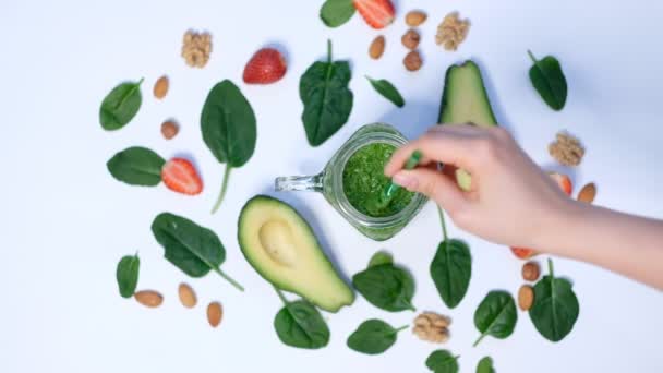 Egészséges vegán zöld spenót Smoothie. spenót és avokádó fehér háttér felülnézetben. A főzés közelsége lassított felvételen - Felvétel, videó