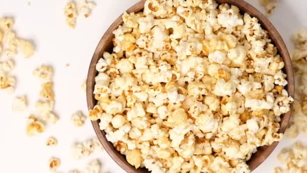 Popcorn tossed in a wooden bowl on a white background. Slow Motion video. Close up top view - Footage, Video
