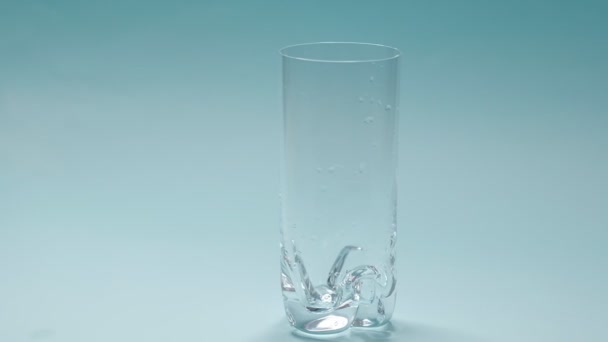 sesión de estudio de agua vertiendo en vidrio transparente sobre fondo azul. Vídeo en cámara lenta. Vista superior cercana
 - Imágenes, Vídeo