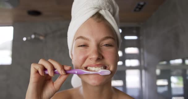 Front view of a beautiful Caucasian woman enjoying quality time in a hotel bathroom, brushing teeth in bathroom, slow motion - Filmmaterial, Video