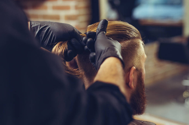 Creating new hair look. Young bearded man getting haircut by hairdresser. - Фото, зображення