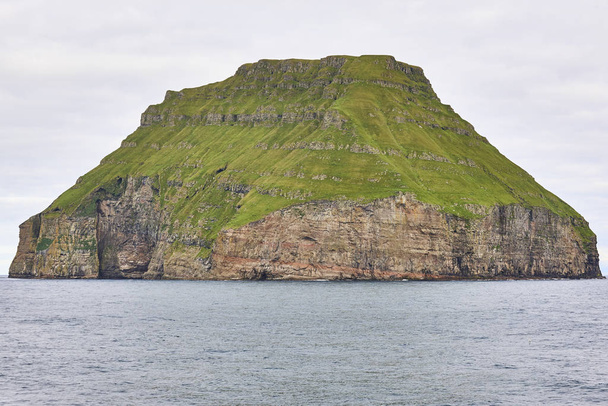 Rocky island with green slopes in Faroe archipelago and ocean - Photo, Image