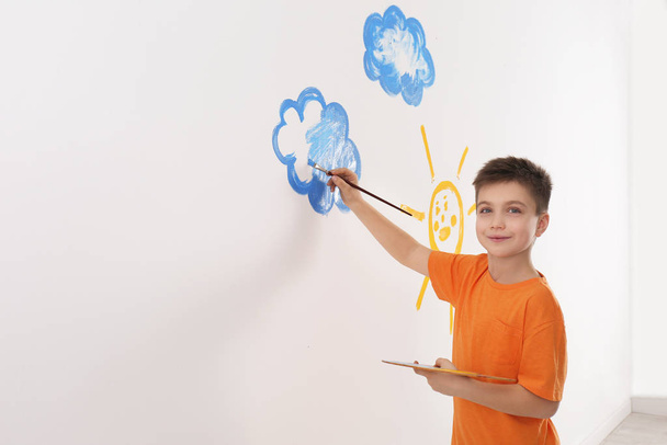 Little child painting cloud on white wall in room - Zdjęcie, obraz