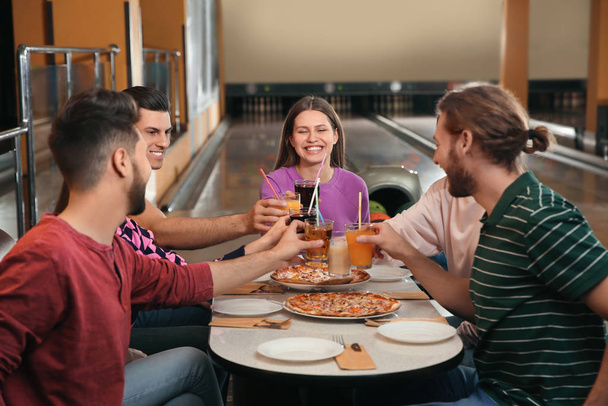 Group of friends with drinks and pizza in bowling club - 写真・画像