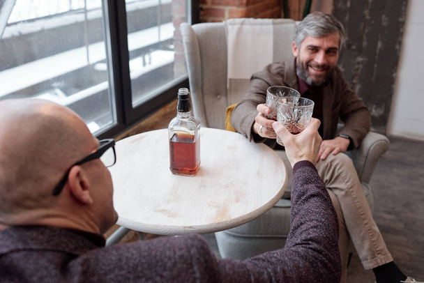 友人と飲みながらウイスキーグラスで味わうガラスの中のはげ男の肩のビュー - 写真・画像